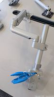 Full view of silver monitor arm mounted to desk rail
