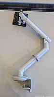 Full view of monitor arm mounted on desk showing articulation and VESA plate