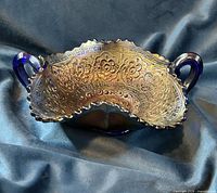 Oblique view of bowl highlighting interior pattern, iridescence, handles, ruffled rim