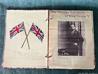 Scrapbook open to first pages: hand-painted Union Jack flags and King George V clipping