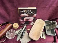 All items grouped: cookbook, pans, tools, dish, leather carrier