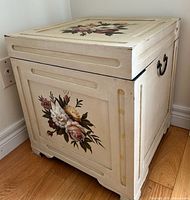 Angled view showing top floral painting, front panel and overall form