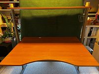 Front view of desk showing brown desktop, silver frame, upper shelf, attached baskets