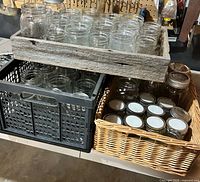 Three containers each filled with clear glass mason jars, some with white lids
