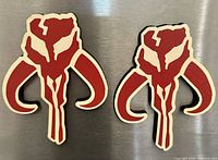 Front view of both Mythosaur skull magnets on metallic surface