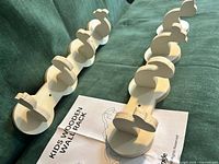 Two wooden wall racks on green fabric with instruction sheet