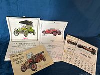 Group shot of six antique car calendars, covers and sample pages visible