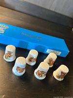 Six porcelain teddy bear thimbles with blue Keepsakes box