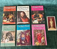 Six devotional guide booklets and prayer card arranged on surface