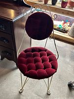 Full view of chair showing red tufted velvet seat and back, metal frame and legs