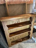 Front view of wooden shelf showing three tiers and scalloped sides