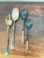 Front view of four large serving utensils showing two silver-plated pieces and two Bakelite pieces