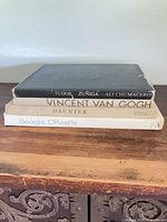 Stack of four large art books on wooden surface