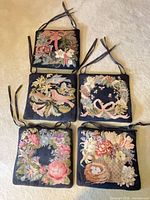 All five needlepoint seat cushions with ties displayed together