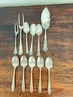 Group view of all eleven flatware pieces laid out on wooden surface