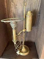 front view of brass student lamp showing base, reservoir and shade ring
