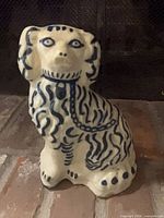 Front view of cobalt blue and white spaniel figurine showing facial features and chest chain