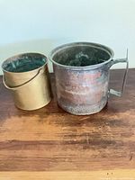 Front view of brass bucket and copper pot displaying sizes, handles, etched decoration