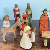 Front view of painted wood figures including donkey with rider, three wise men, Mary, Joseph, angels, cow