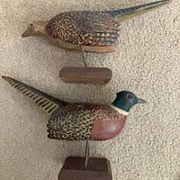Side view of both carved pheasant decoys on their bases