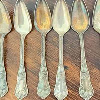 Front view of six silver plated spoons showing floral handle design
