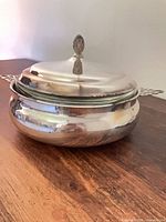 Overall view of silver-plate casserole with lid fitted, showing form and shine