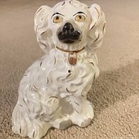 Front view of white ceramic spaniel figurine showing face, collar and gilded fur details