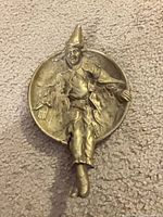 Front view of brass Pierrot clown ashtray showing bowl and figure details