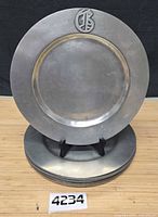 Front view of one plate on stand with stack beneath, shows monogram and overall design