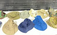 Full group of 11 assorted bucket and boonie hats on table