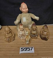Group shot of four chalkware figures, one ceramic figure and plush doll