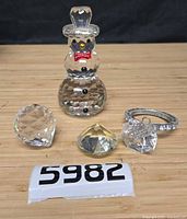 Group shot of all items: crystal snowman, three prisms, silver-tone ring