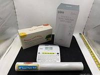 Group shot of all four items: label maker, diffuser box, ceramic set box, easel paper roll