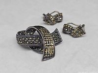 Front view of brooch and earrings showing design and stone setting