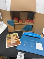 Open shipping carton showing boxed base station, keypad, three entry sensors, motion sensor, SimpliCam, video doorbell and literature