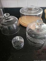 Group shot showing four glass domes and wood base on countertop