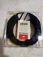 Overall view of sealed Zippo belt buckle package showing black woven belt and branded insert