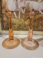 Front view of both pink depression glass candlestick holders showing overall form and gold banded bases