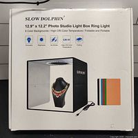 Retail box front showing Slow Dolphin 12.9 x 12.2 in photo studio light box details and included backdrops
