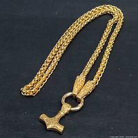 Full view of gold tone stainless steel chain with hammer pendant attached