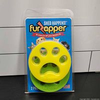 Front of sealed FurZapper 2-pack showing yellow and green discs in packaging