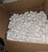 Open box filled with numerous small white plastic bottles