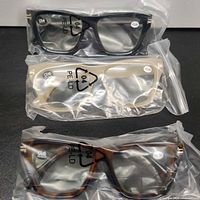 Three bagged pairs of reading glasses in black, beige translucent and tortoiseshell frames