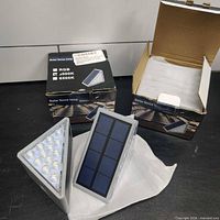 Two boxed and two unboxed triangular solar lights shown