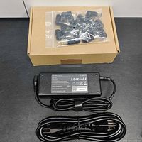Adapter brick, power cord and bag of 15 tips displayed with cardboard box