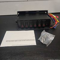 Front view of switch panel showing six rocker switches, wiring harness, screws and manual