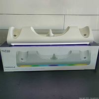 Front view of white TNORACLE charging dock in packaging