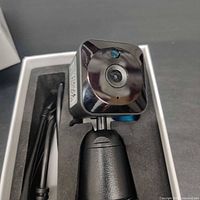 Camera on stand inside box showing lens and USB cable