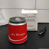 Complete lot showing red ozone air purifier, USB cable, and box