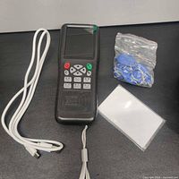 Complete lot showing programmer, USB cable, wrist strap, bag of blue fobs, stack of white cards